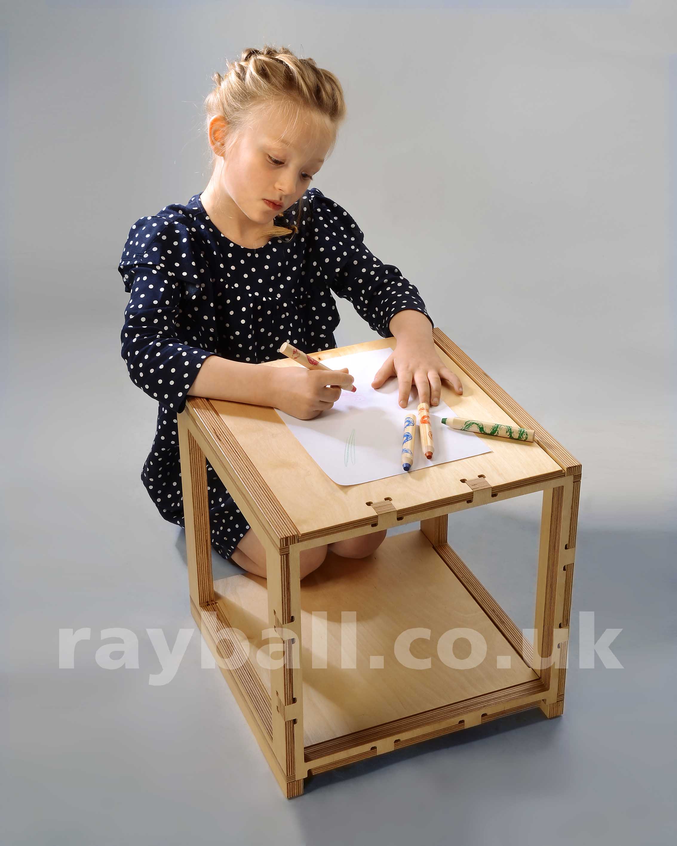 Young Tolworth girl in poker dot dress from Worcester Park crayoning on table made in Sutton.