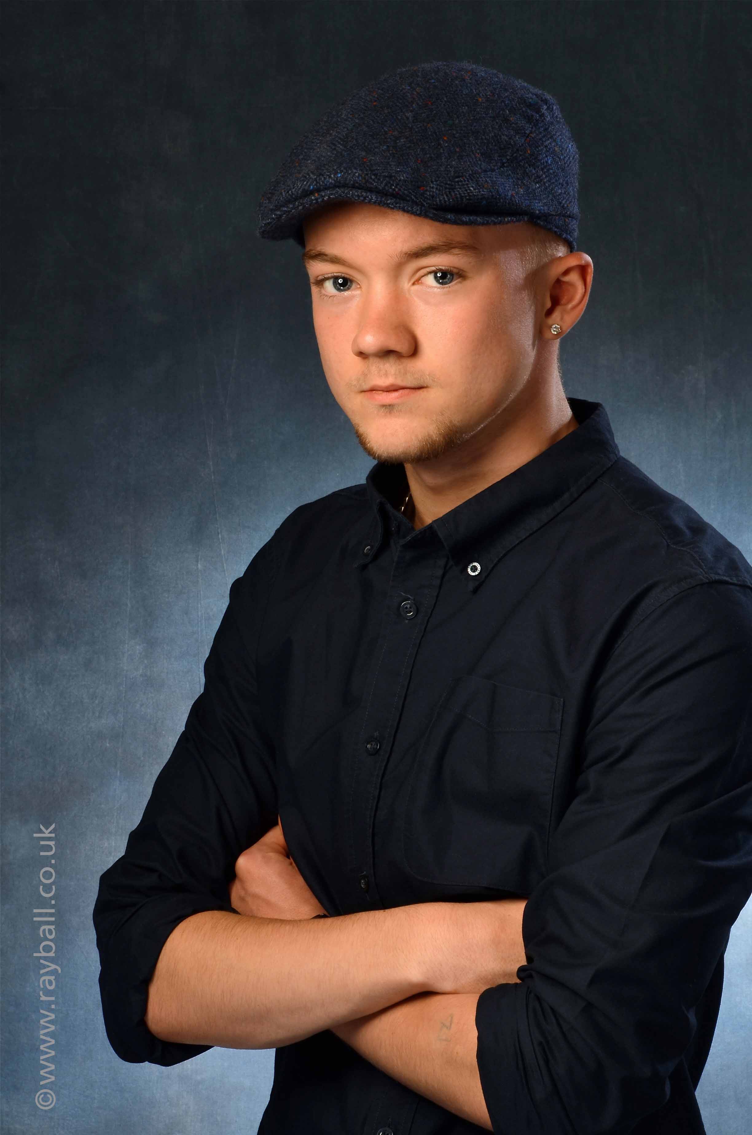 Headshot of male drams student in black shirt and cap.